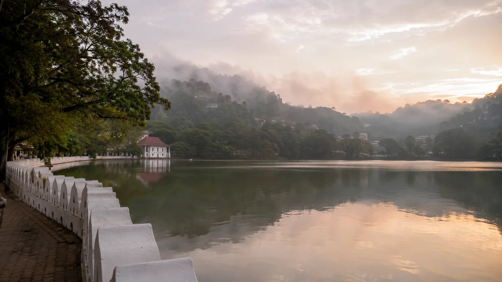 Kandy Lake at misty sunrise with the white lakeside parapet