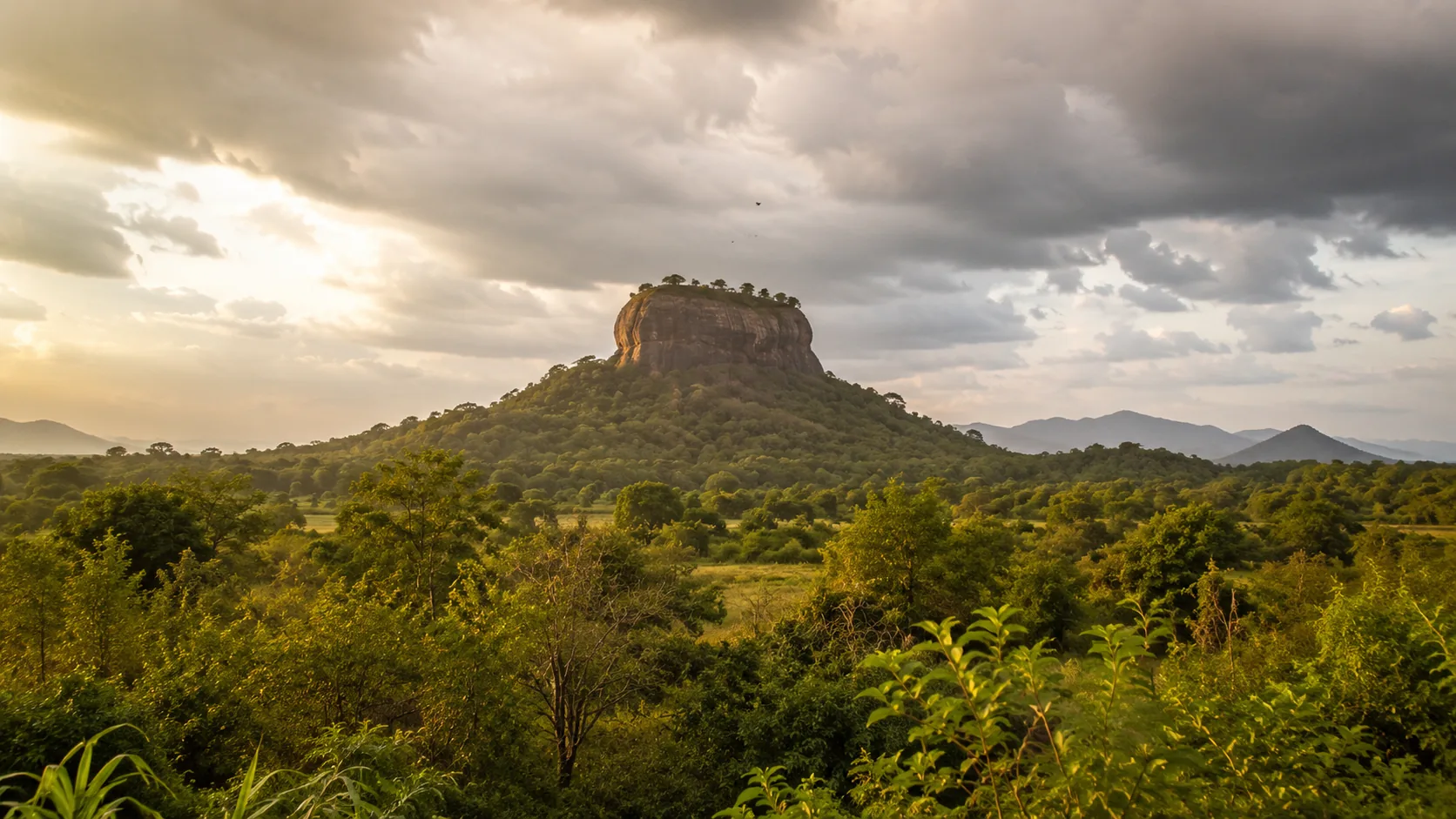 Sigiriya rock rising above scrub jungle under monsoon clouds